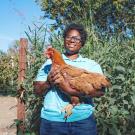 Marvette holds Pumpkin the chicken in the chicken coop